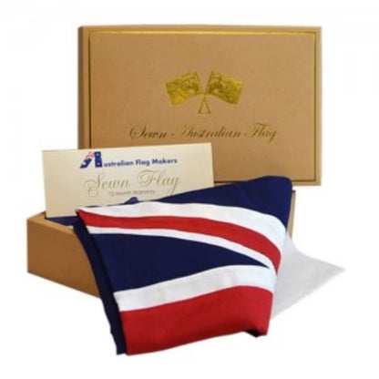 An Australian flag gift set from Sevn Flag, featuring a folded red, white, and blue Australian flag, a gold-colored presentation box with gold foil branding, and a white branded card.